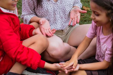 Uluslararası Çocuk Günü. Latin anne dışarıda çocuklarıyla eğleniyor. Yerde oturup, elleriyle oynuyorlar. Aile kavramı. İki küçük çocuğu olan bekar bir anne..