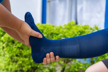 Ev hemşiresi, kırık ayaklı, sıkıştırılmış genç bir kadına açık hava terapisi yapıyor. Fraktür kaval kemiği sağlık ve bakım konsepti. Koltuk değnekleriyle yürüyorum.