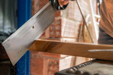 Evde testere ile çalışan yaşlı bir adam. Latinler odun kesip onarıyor. Marangozluk aletleri. Ön planda yüzük var. Boşluğu kopyala.