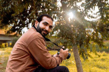 Uzun saçlı, sakallı Latin fotoğrafçı, yolculuğunun tadını çıkarıyor ve belgeliyor. Dünya fotoğrafçılık günü. Tatil ve seyahat.