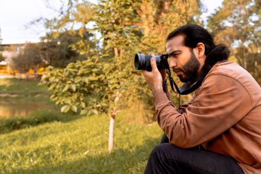 Uzun saçlı, sakallı Latin fotoğrafçı, yolculuğunun tadını çıkarıyor ve belgeliyor. Dünya fotoğrafçılık günü. Tatil ve seyahat.