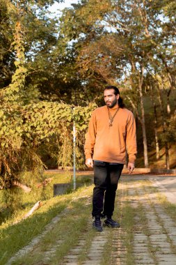 Kahverengi ceketli, uzun saçlı, sakallı Latin bir adam tatilini belgeliyor ve ülkesinin altın saatinin tadını çıkarıyor. Dünya fotoğrafçılık ve seyahat günü. 