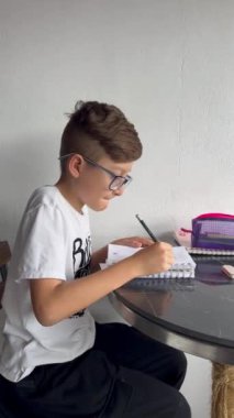 Gözlüklü Latin çocuk defterine resim çiziyor. Okula, çocukluğa. Ödev ve dersler