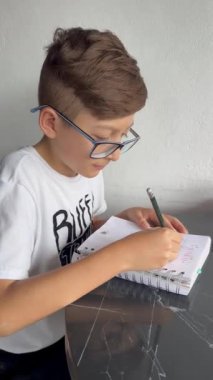 Gözlüklü Latin çocuk defterine resim çiziyor. Okula, çocukluğa. Ödev ve dersler