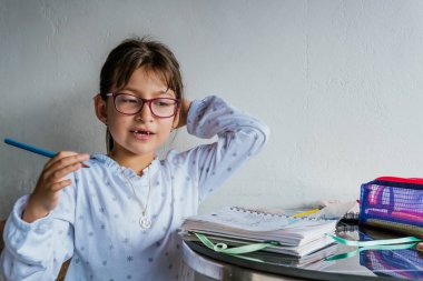 Gözlüklü Latin kız evde iş yapıyor. Defteri boyuyorum. Okula dönelim. Çocukluk ve resim.