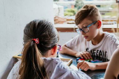 Gözlüklü Latin çocuklar, evde ders çalışıyorlar ve ödev yapıyorlar. Okula dönelim. Çocukluk. Öğrenme ve beceriler.