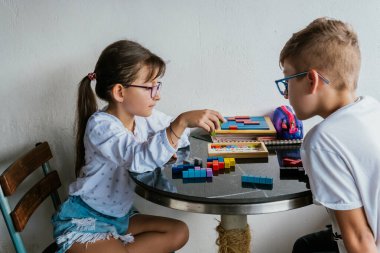 Gözlüklü Latin çocuklar, evde ders çalışıyorlar ve ödev yapıyorlar. Okula dönelim. Çocukluk. Öğrenme ve beceriler.