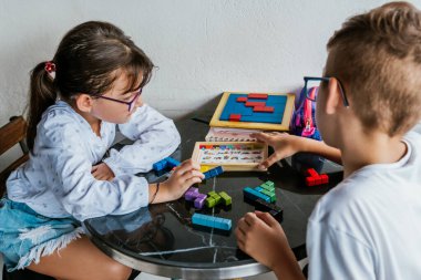 Gözlüklü Latin çocuklar, evde ders çalışıyorlar ve ödev yapıyorlar. Okula dönelim. Çocukluk. Öğrenme ve beceriler.