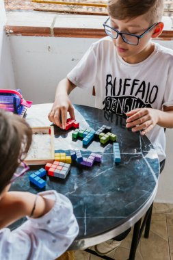 Gözlüklü Latin çocuklar, evde ders çalışıyorlar ve ödev yapıyorlar. Okula dönelim. Çocukluk. Öğrenme ve beceriler.