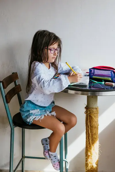 Gözlüklü Latin kız evde iş yapıyor. Defteri boyuyorum. Okula dönelim. Çocukluk ve resim.