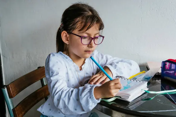Gözlüklü Latin kız evde iş yapıyor. Defteri boyuyorum. Okula dönelim. Çocukluk ve resim.