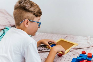 Gözlüklü Latin çocuk defterine resim çiziyor. Okula, çocukluğa. Ödev ve dersler.