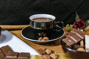 Çikolata parçalı kurabiyeler, siyah beyaz çikolatalar, küçük bir kase yulaf ezmesi ve fındık. Uluslararası Çikolata Günü.