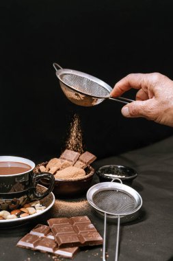 Çikolata parçalı kurabiyeler, siyah beyaz çikolatalar, küçük bir kase yulaf ezmesi ve fındık. Uluslararası Çikolata Günü.