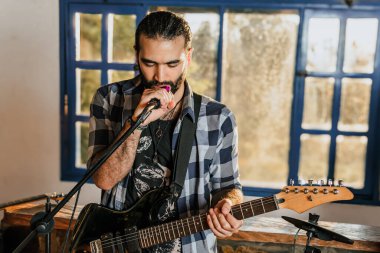 Elektro gitar çalan erkek şarkıcı. Grubun provası evde. Uluslararası müzik günü.