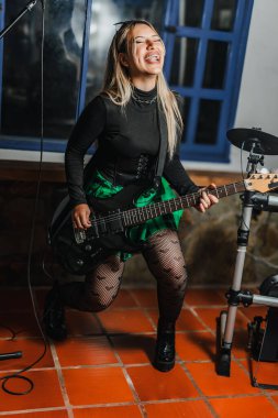 Bas gitar çalan kadın şarkıcı. Grubun provası evde. Uluslararası müzik günü.