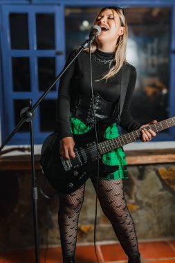 Bas gitar çalan kadın şarkıcı. Grubun provası evde. Uluslararası müzik günü.