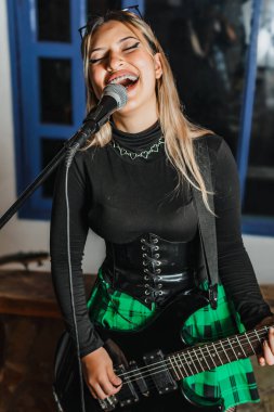 Bas gitar çalan kadın şarkıcı. Grubun provası evde. Uluslararası müzik günü.