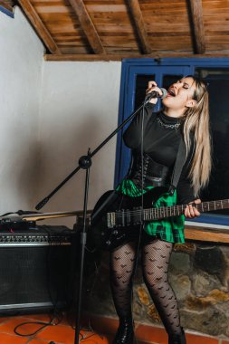 Bas gitar çalan kadın şarkıcı. Grubun provası evde. Uluslararası müzik günü.