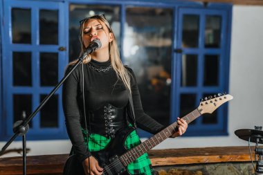Bas gitar çalan kadın şarkıcı. Grubun provası evde. Uluslararası müzik günü.