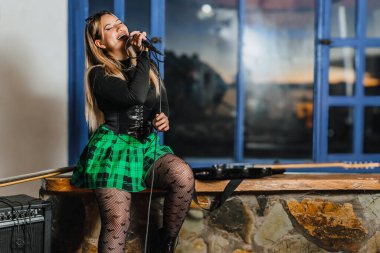 Bas gitar çalan kadın şarkıcı. Grubun provası evde. Uluslararası müzik günü.