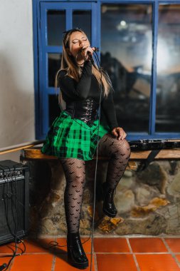 Bas gitar çalan kadın şarkıcı. Grubun provası evde. Uluslararası müzik günü.