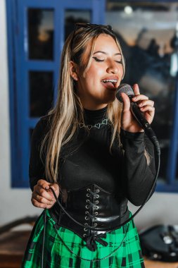 Bas gitar çalan kadın şarkıcı. Grubun provası evde. Uluslararası müzik günü.
