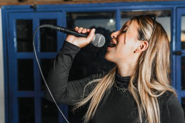 Bas gitar çalan kadın şarkıcı. Grubun provası evde. Uluslararası müzik günü.