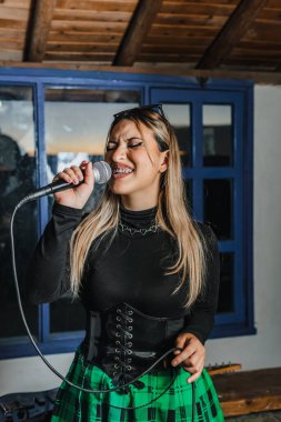 Bas gitar çalan kadın şarkıcı. Grubun provası evde. Uluslararası müzik günü.