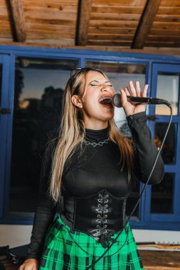 Bas gitar çalan kadın şarkıcı. Grubun provası evde. Uluslararası müzik günü.