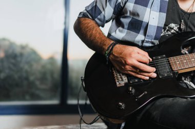 Sakallı bir adam elektro gitar çalıyor. Grubun provası evde. Uluslararası müzik günü.