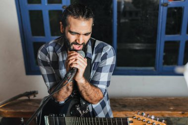 Elektro gitar çalan erkek şarkıcı. Grubun provası evde. Uluslararası müzik günü.