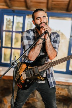 Elektro gitar çalan erkek şarkıcı. Grubun provası evde. Uluslararası müzik günü.