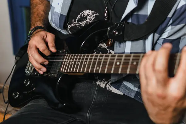 Sakallı bir adam elektro gitar çalıyor. Grubun provası evde. Uluslararası müzik günü.