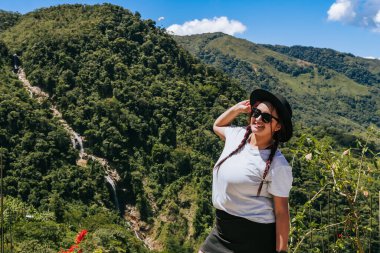 Kolombiya 'da tatilde gülümseyen güneş gözlüklü ve şapkalı güzel bir kadın. İnsanlar gülümsüyor. Manzara ve seyahatler.