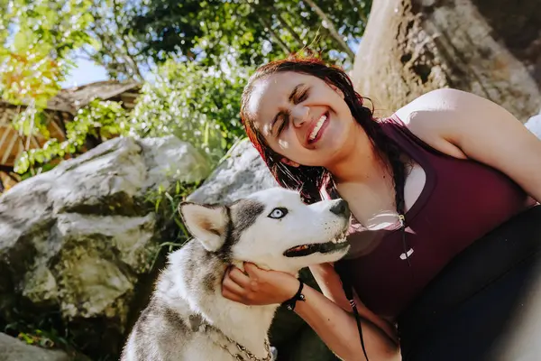 stock image Latin woman with her faithful dog smiling in the river. People smiling. Refreshing sunny day at waterfall in Colombia.