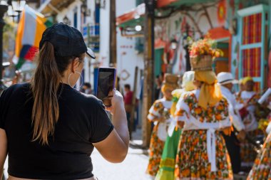 Kadın gezgin, antik köy kültürünün fotoğraflarını çekiyor. Guatape. Dans ve gelenek.