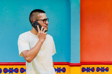 Yolda konuşurken cep telefonuyla konuşan Latin bir adam. Kolombiya şehirleri.