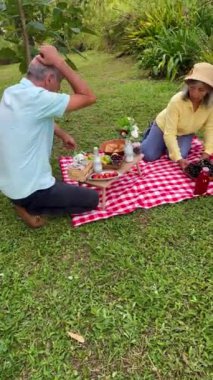 Evli çift piknik gününü paylaşıyor. İnsanlar gülümsüyor. Ağaçlar ve doğa. Mutlu Latinler.