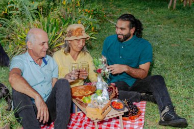 Oğlu piknik gününü ailesiyle paylaşıyor. İnsanlar yudumluyor. Mutlu Latin ailesi.