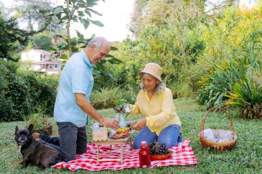 Çift, aile pikniği için eşyalarını hazırlıyor. İnsanlar gülümsüyor.