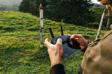 Gezgin bir adam kırsal bir alanda insansız hava aracı uçuruyor, doğa ve bitki örtüsü. Seyahat ve yol.