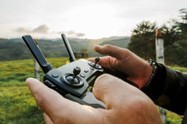 Gezgin bir adam kırsal bir alanda insansız hava aracı uçuruyor, doğa ve bitki örtüsü. Seyahat ve yol.