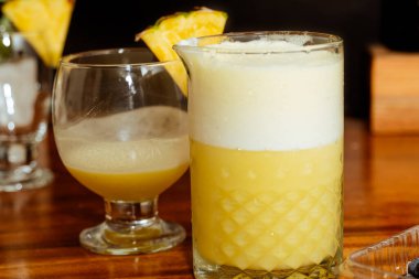 Ahşap masa ve siyah arka planda ferahlatıcı kokteylleri karıştıran adam.