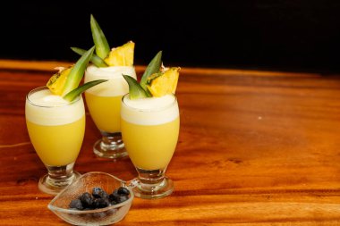 Ahşap masa ve siyah arka planda ferahlatıcı kokteylleri karıştıran adam.