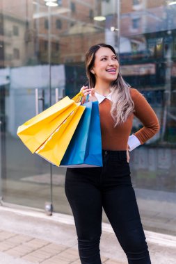 Ürünleriyle mutlu alışveriş yapan kadın siyah cuma günü sarı ve mavi çantalı. İnanılmaz indirimler..