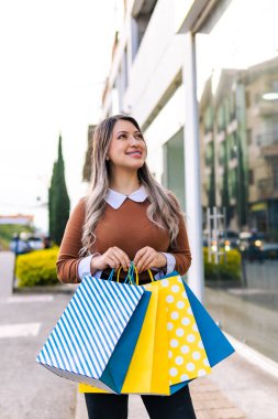 Ürünleriyle mutlu alışveriş yapan kadın siyah cuma günü sarı ve mavi çantalı. İnanılmaz indirimler..