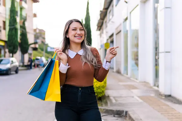 Ürünleriyle mutlu alışveriş yapan kadın siyah cuma günü sarı ve mavi çantalı. İnanılmaz indirimler..