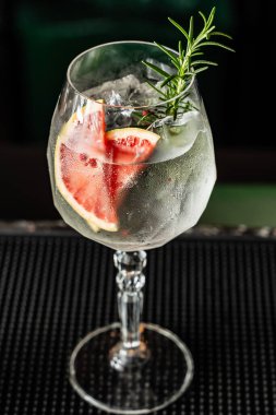 Güzel bir barda greyfurtlu ve biberiyeli cin ve tonik karışımını tazeliyorum..