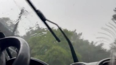 Dikkatli sürerken araba esintileri için yağan yağmurun videosu. Camdaki küçük buz parçaları..
